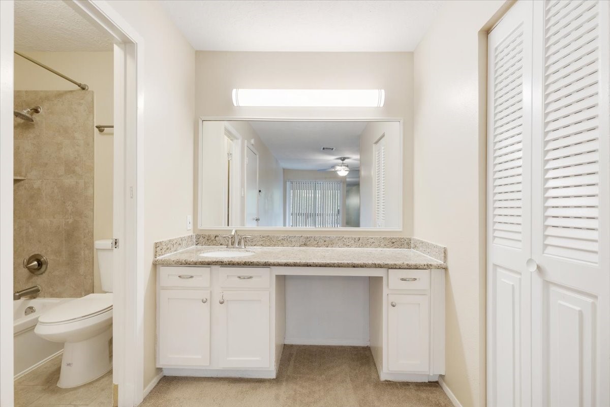 3502 Ocee Street, Unit 3502 Houston, TX 77063 - Photo 17 of 28 This photo showcases a bright bathroom with a granite countertop vanity, ample storage, and a large mirror. The adjacent area reveals a shower-tub combo with tiled walls.