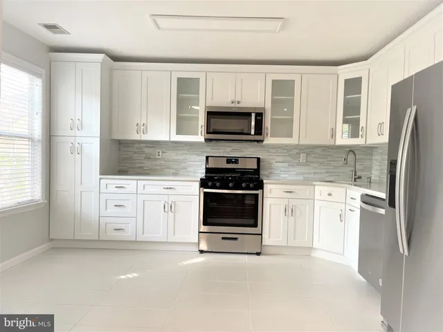 a kitchen with white cabinets and stainless steel appliances