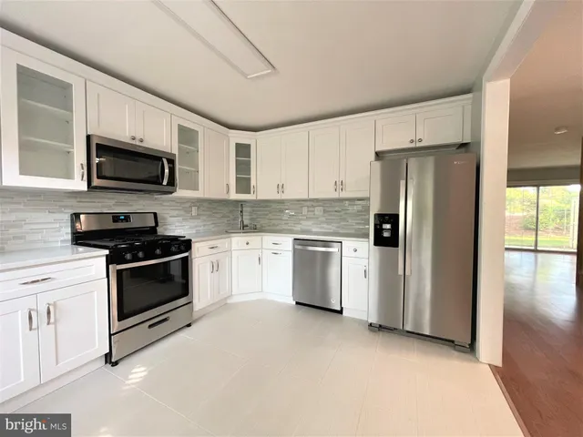 a kitchen with stainless steel appliances white cabinets and a stove top oven