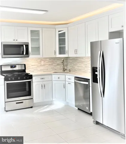a kitchen with stainless steel appliances white cabinets and a refrigerator