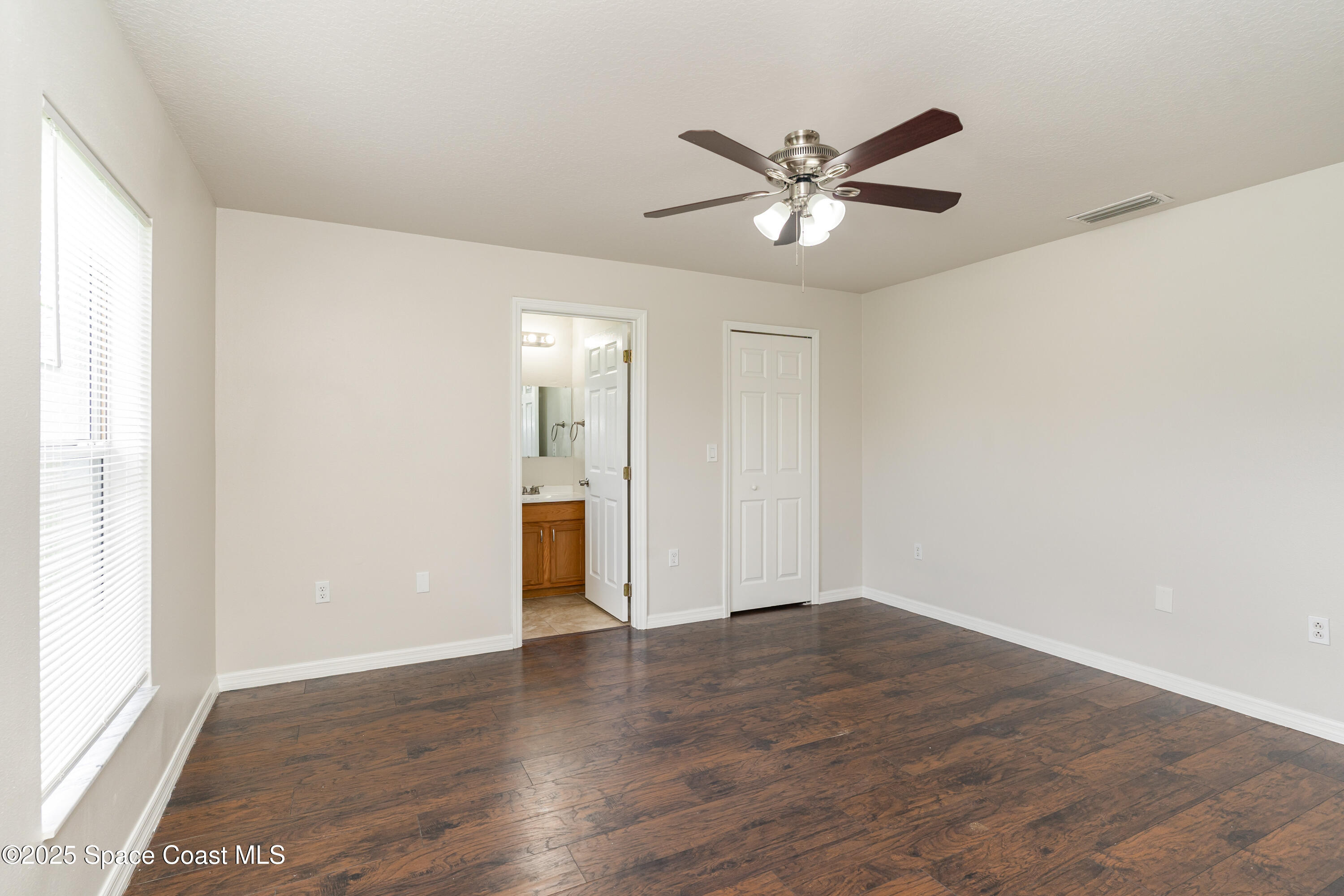 774 Fletcher Road Southeast Palm Bay, FL 32909 - Photo 8 of 20 a view of an empty room with wooden floor and a window