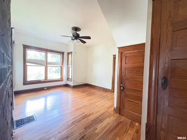 a view of empty room with wooden floor and fan