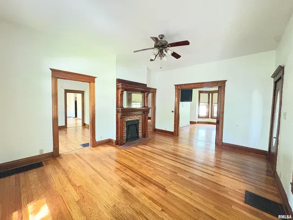 a view of an empty room with window and wooden floor