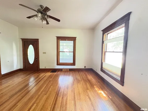 a view of empty room with wooden floor and fan