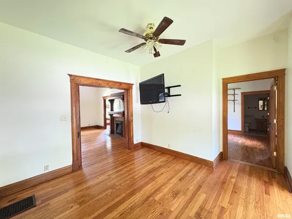 a view of empty room with wooden floor and ceiling fan