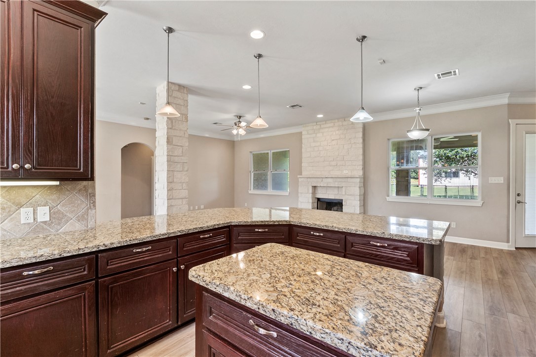 6701 Old Reliance Road Bryan, TX 77808 - Photo 12 of 44 a large kitchen with kitchen island granite countertop wooden floor a large window and stainless steel appliances