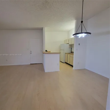a view of an empty room with furniture and a window