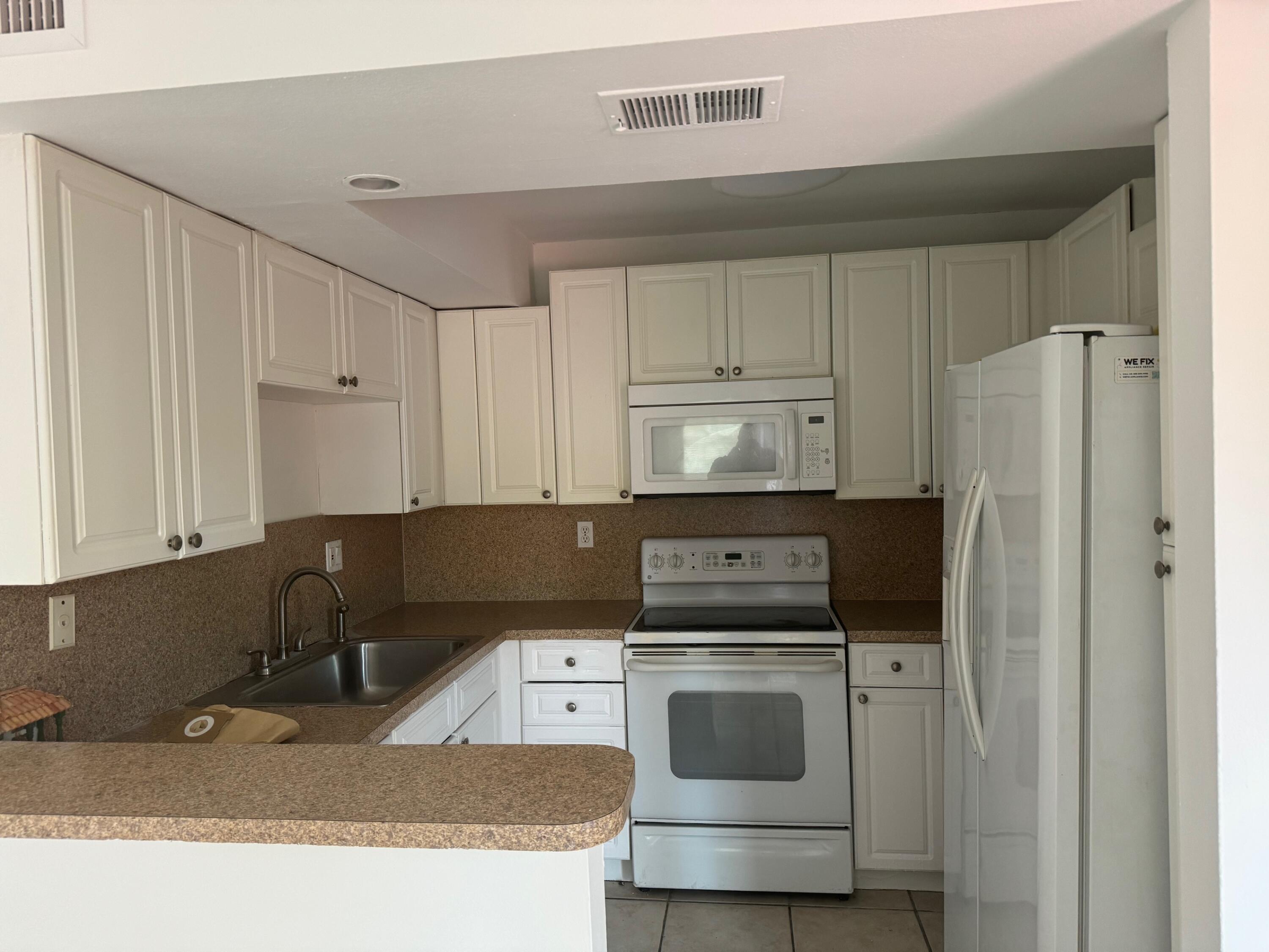 8068 Severn Drive, Unit B Boca Raton, FL 33433 - Photo 10 of 12 a kitchen with a refrigerator sink and cabinets