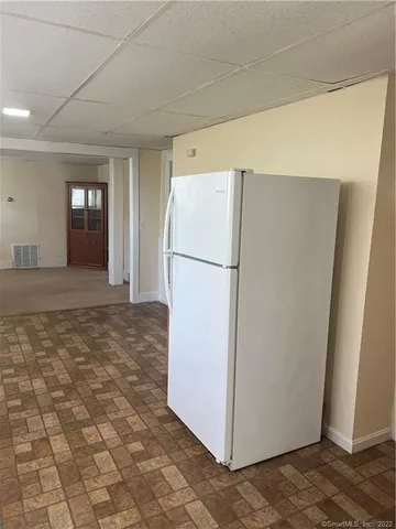 a view of a refrigerator in kitchen and an empty room