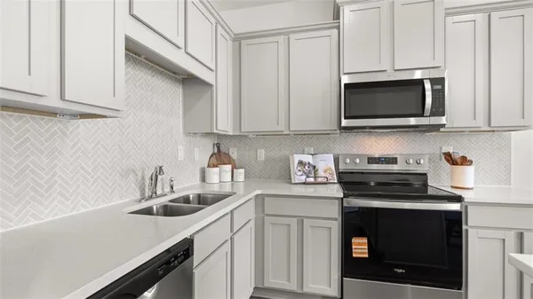a kitchen with white cabinets and black appliances