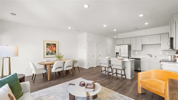 a living room with stainless steel appliances furniture and a kitchen view