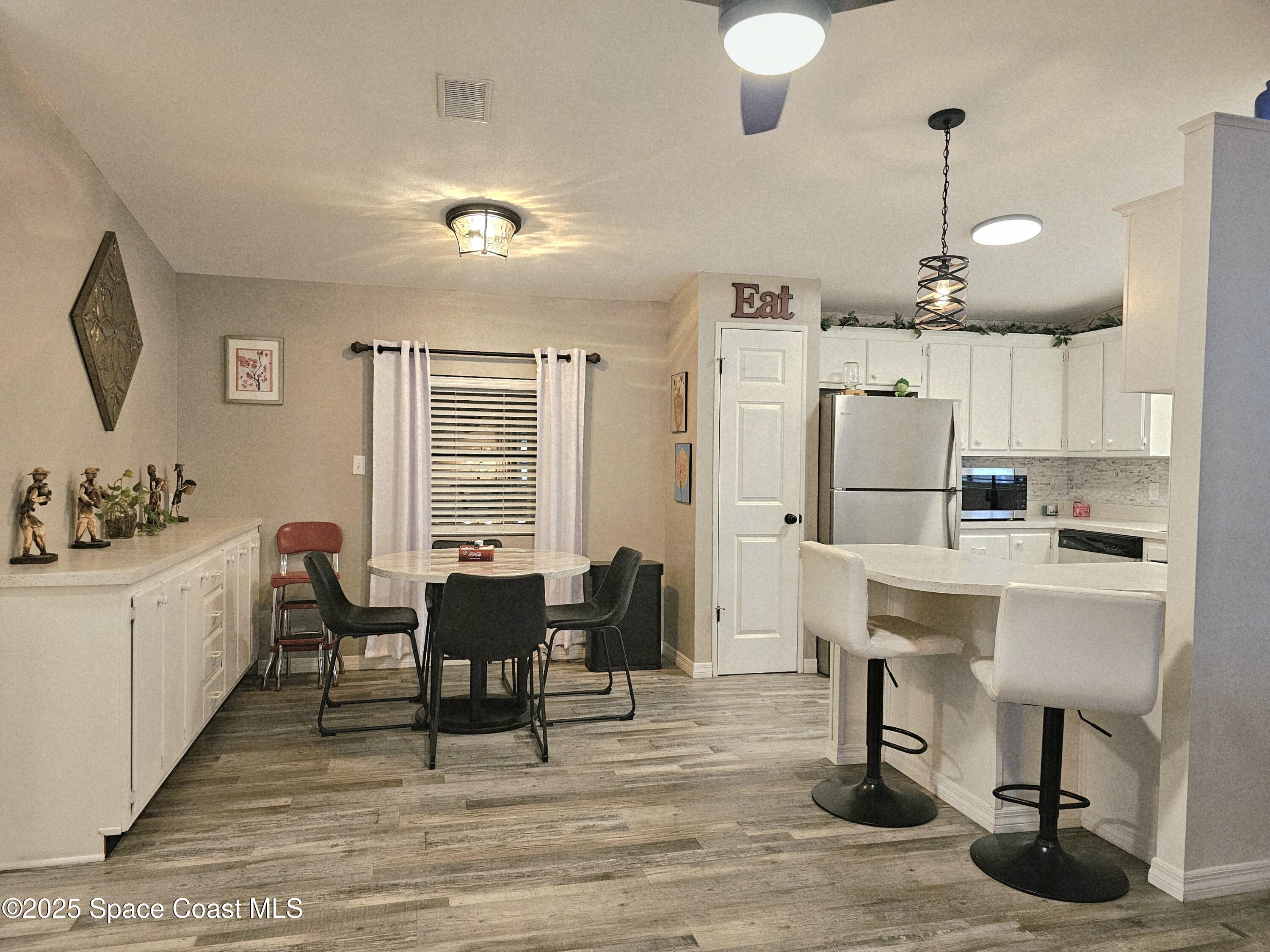 1809 Mango Street Northeast Palm Bay, FL 32905 - Photo 4 of 35 a dining room with wooden floor a chandelier a wooden table and chairs
