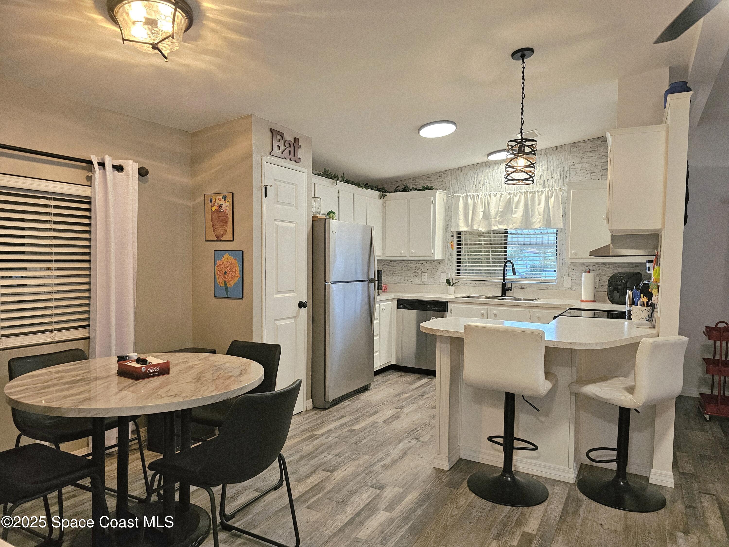 1809 Mango Street Northeast Palm Bay, FL 32905 - Photo 6 of 35 a kitchen with stainless steel appliances kitchen island granite countertop a dining table chairs and white cabinets