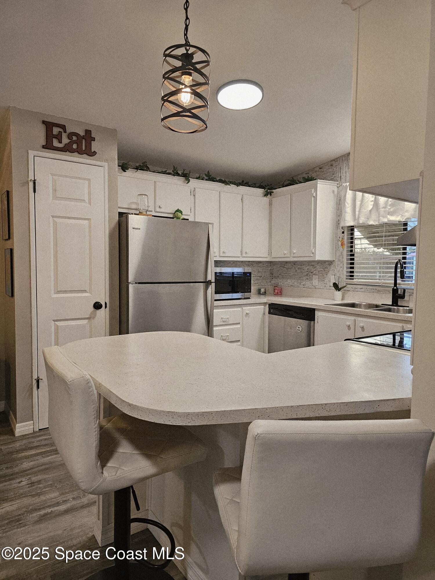 1809 Mango Street Northeast Palm Bay, FL 32905 - Photo 10 of 35 a kitchen with stainless steel appliances kitchen island granite countertop a refrigerator a stove a sink dishwasher and white countertops with wooden floor