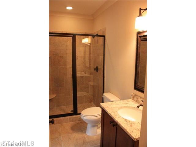 8906 West Pepper Court Oak Ridge, NC 27310 - Photo 10 of 16 Bath. The downstairs guest bath features a walk-in shower and a furniture piece vanity.