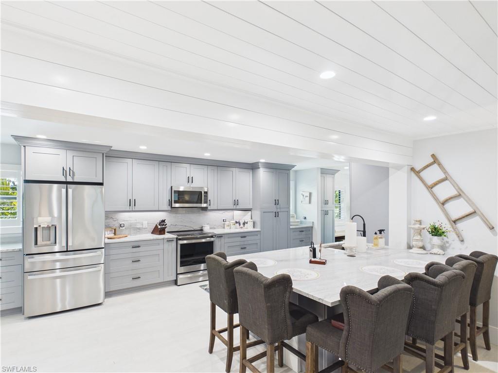 3650 Sunset Boulevard Naples, FL 34112 - Photo 4 of 37 a kitchen with stainless steel appliances a refrigerator a stove a sink dishwasher and white cabinets with wooden floor