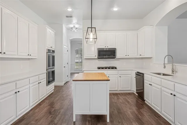 a large kitchen with white cabinets stainless steel appliances and wooden floor