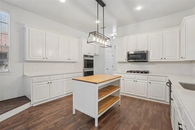 a kitchen with white cabinets stainless steel appliances and wooden floor