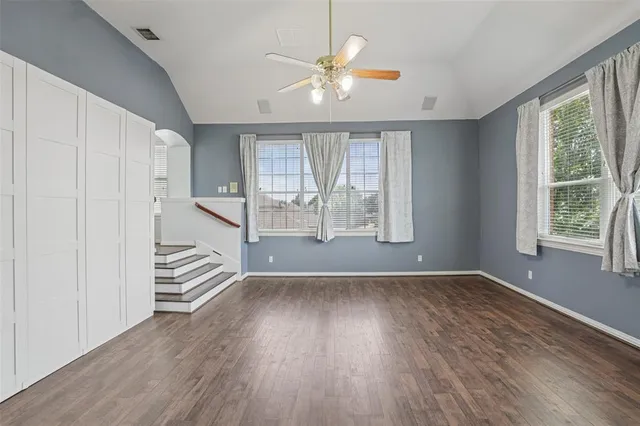 an empty room with wooden floor and windows
