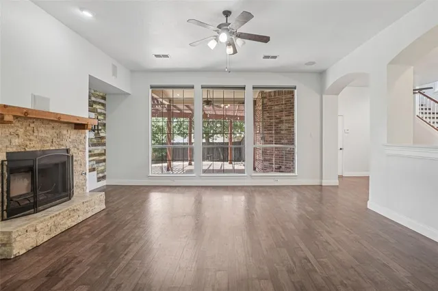 a view of an empty room with wooden floor and a fireplace