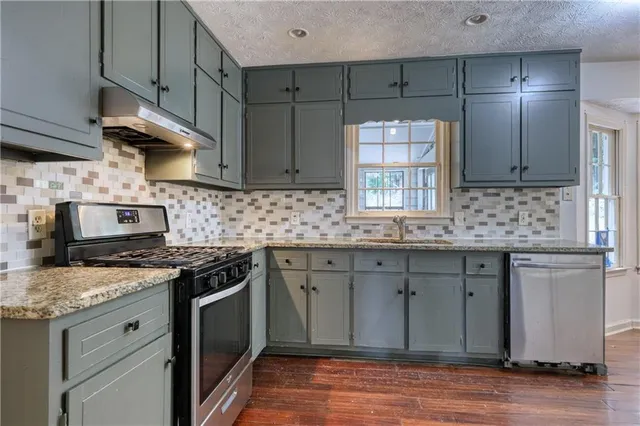 a kitchen with stainless steel appliances granite countertop a sink stove and cabinets