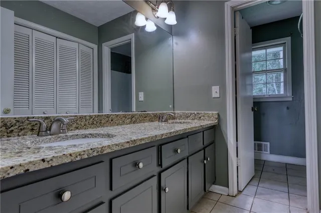 a bathroom with a granite countertop sink a light fixture and a mirror