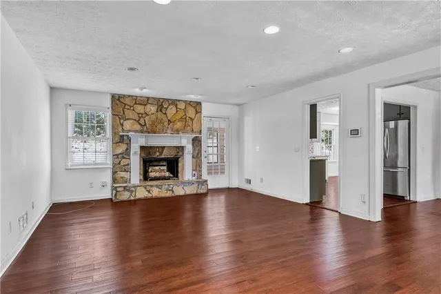 a view of an empty room with wooden floor fireplace and a window