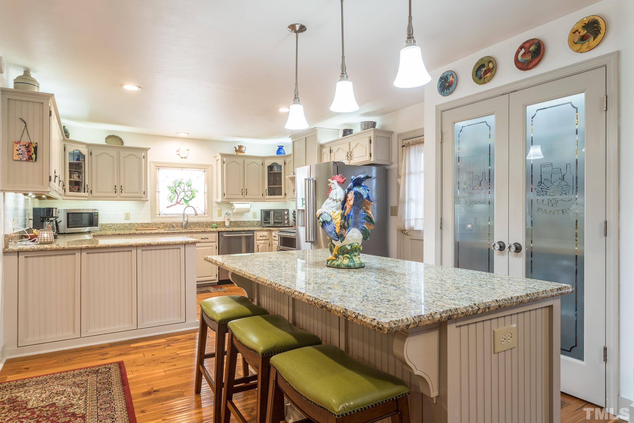 3021 Peebles Road Raleigh, NC 27616 - Photo 12 of 45 a kitchen with granite countertop kitchen island stainless steel appliances a table and chairs in it