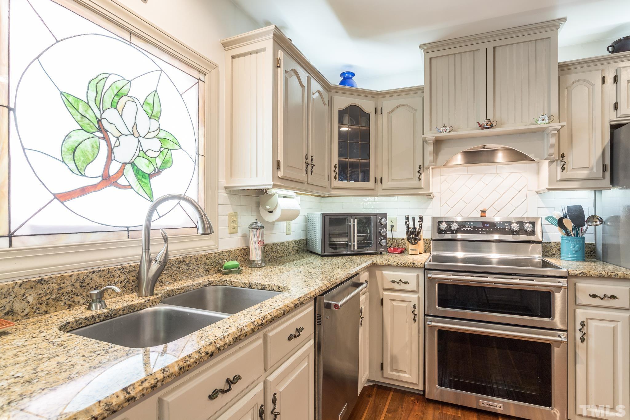 3021 Peebles Road Raleigh, NC 27616 - Photo 17 of 45 a kitchen with granite countertop a sink cabinets stainless steel appliances and a window