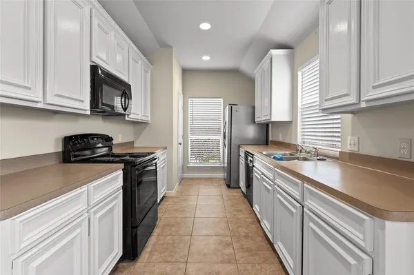 a large kitchen with stainless steel appliances granite countertop a sink a stove and a refrigerator