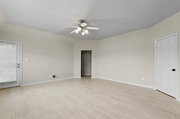 an empty room with chandelier fan and windows