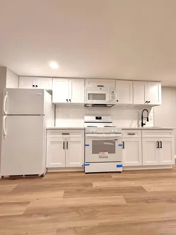 a kitchen with white cabinets and white appliances