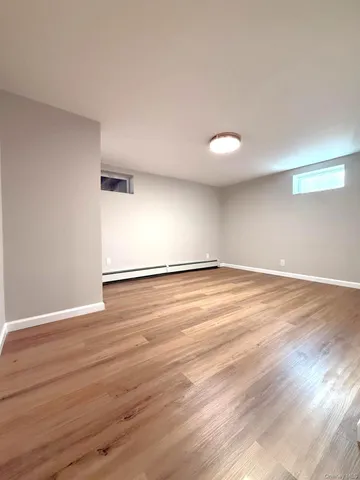a view of an empty room with wooden floor and windows
