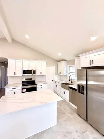 a kitchen with kitchen island a counter top space a refrigerator cabinets and a sink
