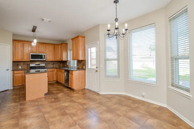 a kitchen with stainless steel appliances granite countertop a stove top oven a sink a refrigerator a window and white cabinets