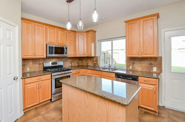 a kitchen with stainless steel appliances granite countertop a stove sink microwave and window