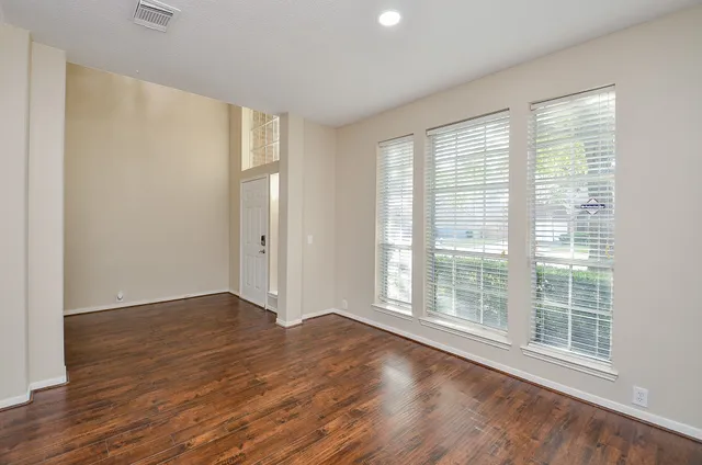 a view of an empty room with wooden floor and a window