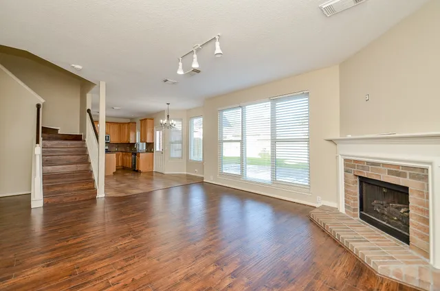 an empty room with wooden floor fireplace and windows