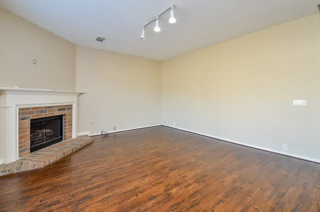 a view of empty room with wooden floor and fireplace