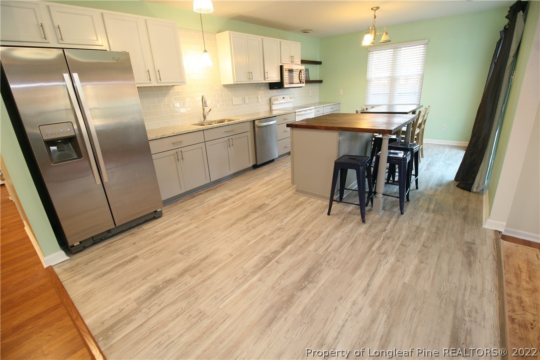6241 Stoney Point Loop Fayetteville, NC 28306 - Photo 14 of 40 a kitchen with stainless steel appliances granite countertop a refrigerator a sink a stove and white cabinets