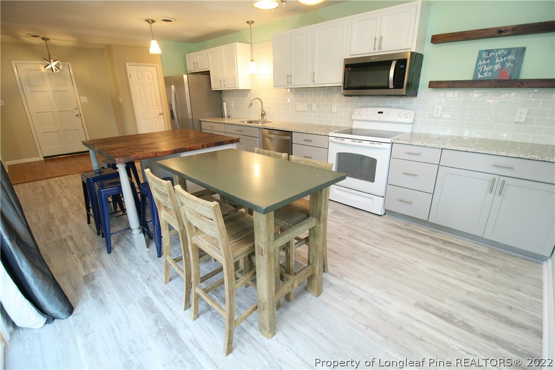 6241 Stoney Point Loop Fayetteville, NC 28306 - Photo 16 of 40 a kitchen with stainless steel appliances kitchen island granite countertop a table chairs microwave and sink