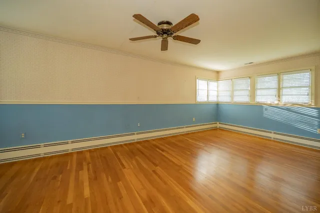 an empty room with wooden floor and windows with curtains