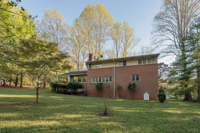 a view of a big house with a big yard and large trees