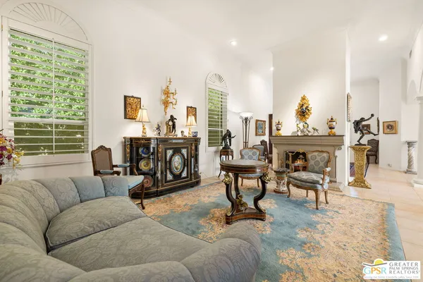 a living room with furniture a fireplace and large windows