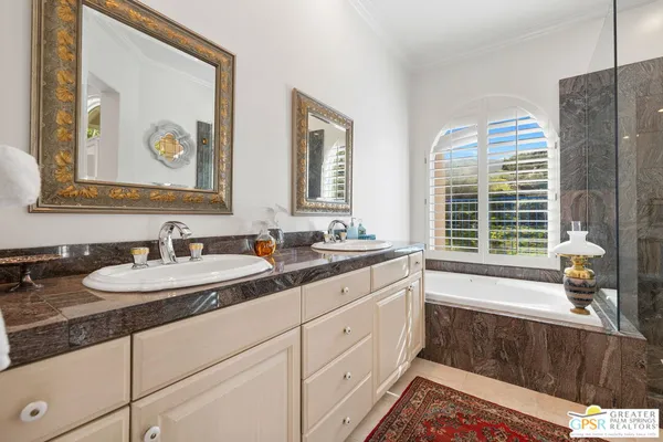 a bathroom with double vanity sinks a large mirror and a window