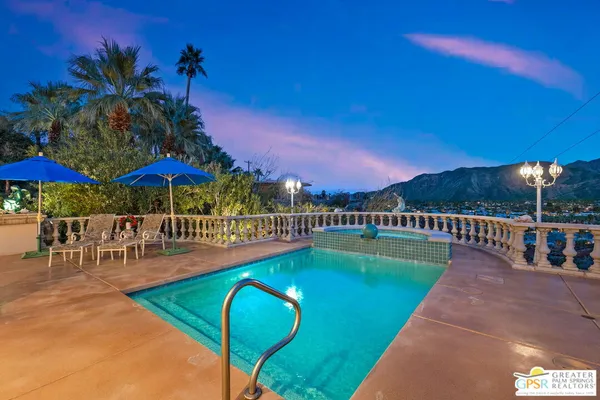 a view of a swimming pool with a table and chairs under an umbrella