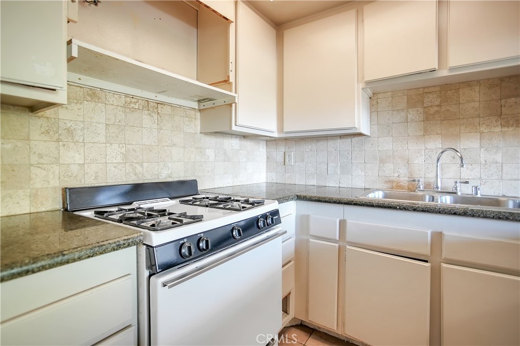 2321 Gonzaga Lane Riverside, CA 92507 - Photo 8 of 24 a white kitchen with granite countertop a stove a sink dishwasher and a microwave oven with white cabinets