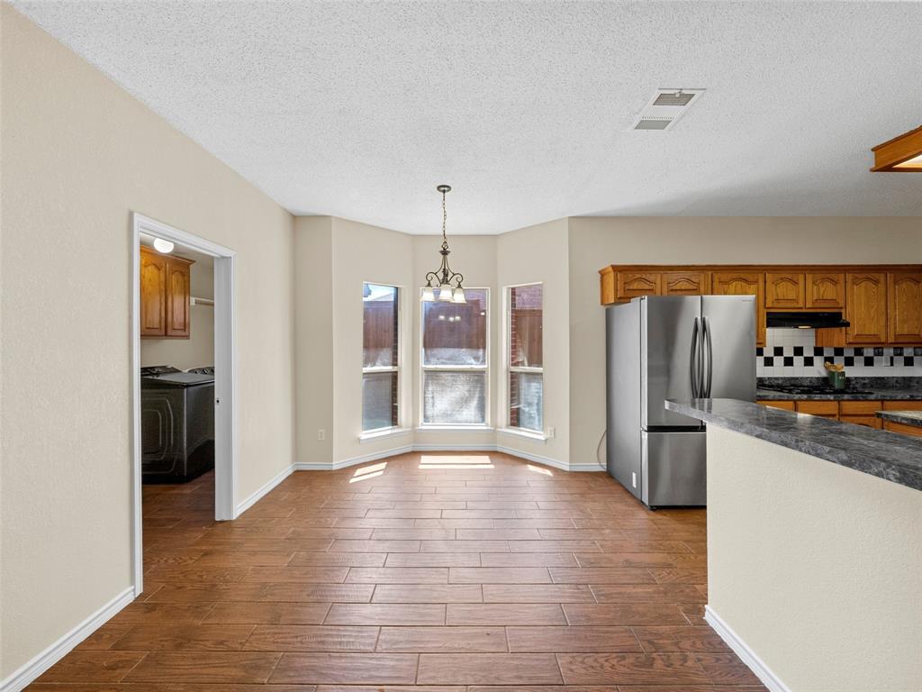 741 Aspen Court Allen, TX 75002 - Photo 18 of 40 Kitchen featuring stainless steel appliances, wood tiled floors, wood finish cabinets, and decorative backsplash