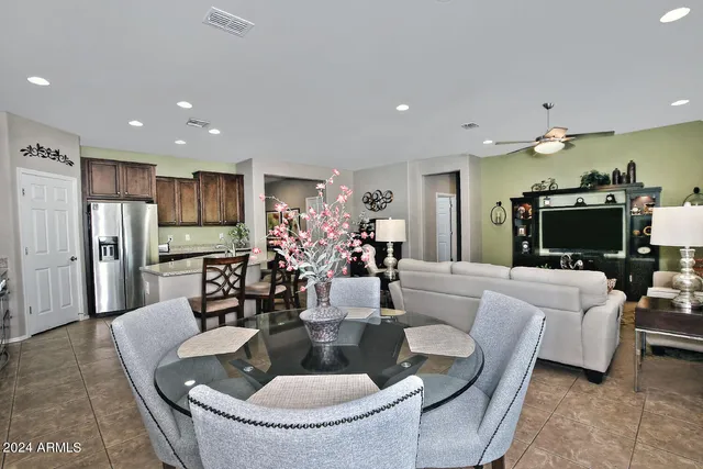a living room with stainless steel appliances furniture a dining table and kitchen view