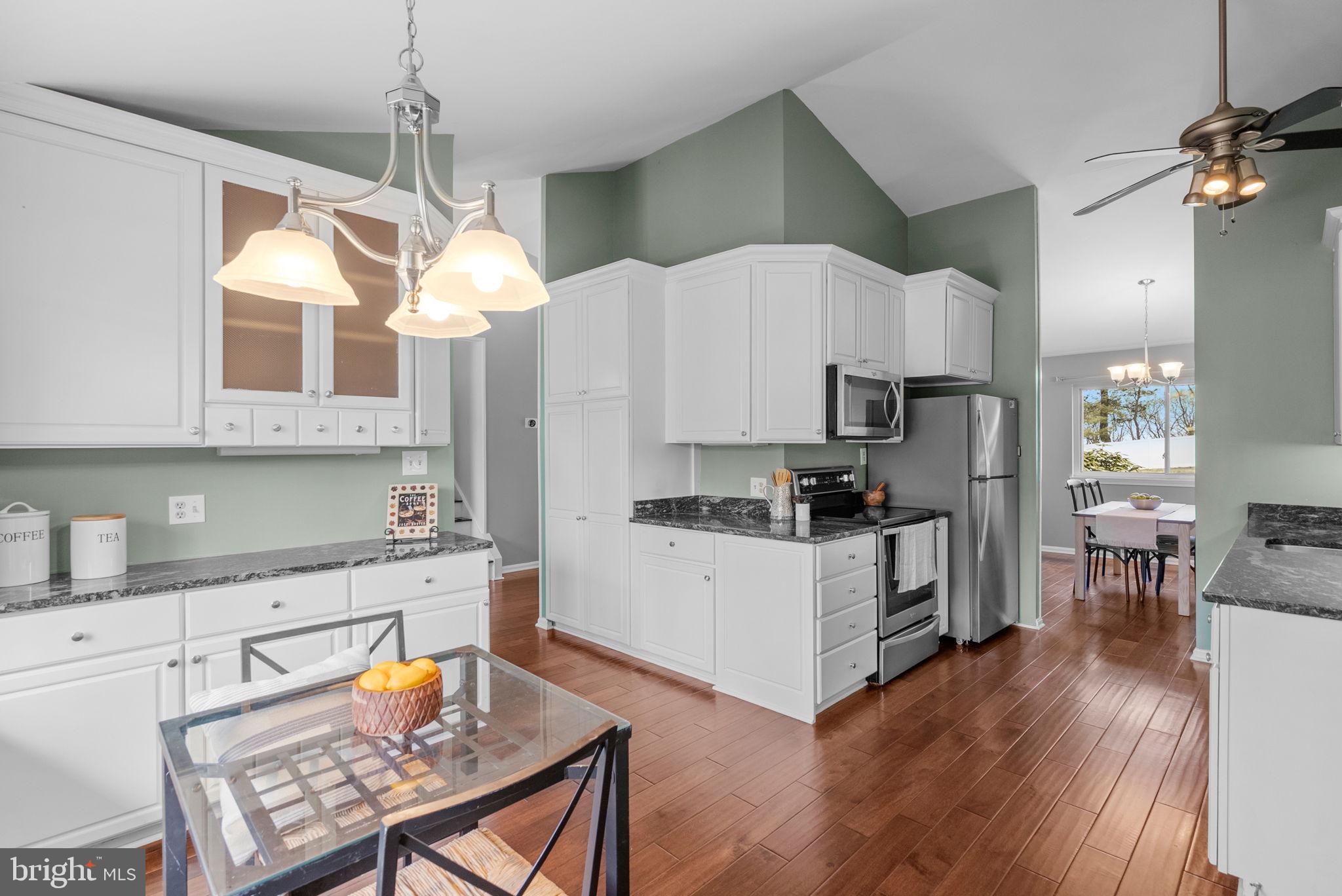 9828 Moyer Road Damascus, MD 20872 - Photo 17 of 46 a kitchen with a refrigerator a stove a sink dishwasher a dining table and chairs with wooden floor